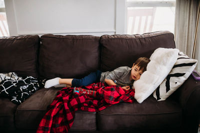 Young boy laying on couch in living room while sick with flu