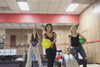 A young woman bowling with friends.