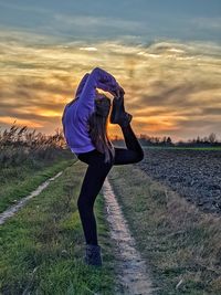 Woman standing on field against sky during sunset