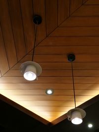 Low angle view of illuminated light bulb hanging from ceiling