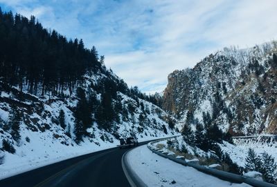 Road amidst snowcapped mountains against sky during winter