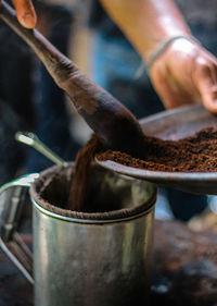 Cropped hand putting roasted coffee bean powder in container