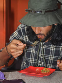 Closeup of a bearded and long haired man with wearing boonie hat during eating noodles in the cafe