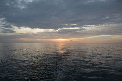 Scenic view of sea against cloudy sky at sunset