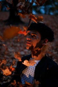 Young man by dry flying leaves at night