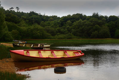 Boat moored on lake against trees