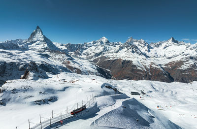 Scenic view of snowcapped mountains against clear blue sky