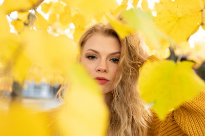 Portrait of young woman with yellow leaves