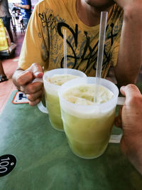 Midsection of man holding coffee cup on table