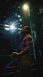 Side view of shirtless man standing in boxing ring