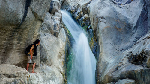 Rear view of man standing at waterfall