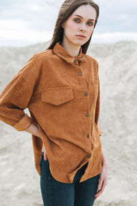 Fashion beauty portrait of young woman in brown organic velvet shirt on desert background