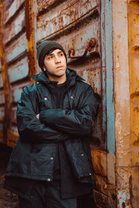 Portrait of young man standing outdoors, against rusty train.