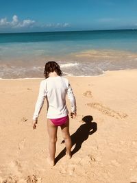 Full length rear view of young woman standing on beach