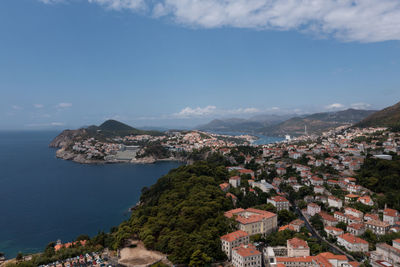 Aerial view of townscape by sea against sky