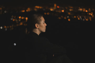 Profile view of woman sitting outdoors at night