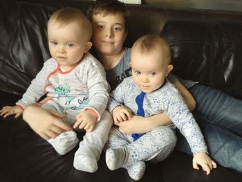 Portrait of brother with twin baby boys relaxing on sofa at home