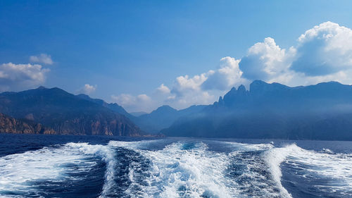 Scenic view of sea by mountains against sky