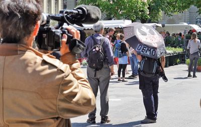 Rear view of people photographing on street