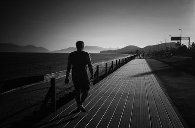 Rear view of man on railing against sky