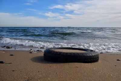 Tire in sand on shore at beach