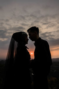 Couple standing against sky during sunset