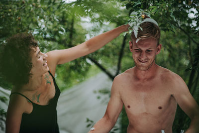 Portrait of shirtless young man against trees