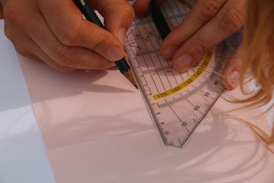 Close-up of woman drawing using ruler on paper
