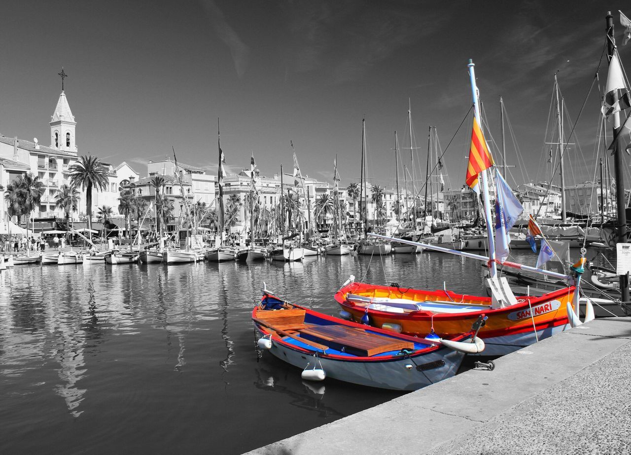 nautical vessel, boat, transportation, moored, mode of transport, water, mast, harbor, sailboat, building exterior, travel, waterfront, river, sea, clear sky, marina, built structure, architecture, outdoors, reflection