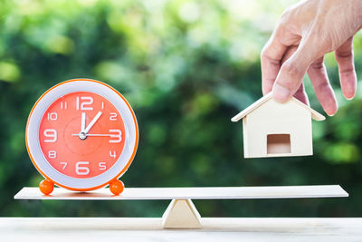 Close-up of hand holding clock against built structure