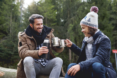 Happy father and daughter toasting coffee at forest