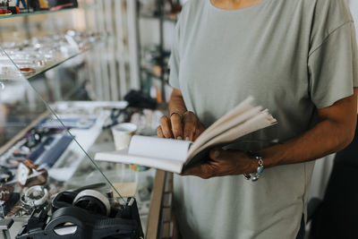 Midsection of saleswoman with diary standing at antique shop