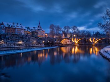 Illuminated bridge over river against sky at night