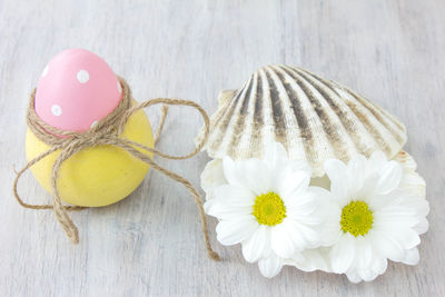 Close-up of eater egg in container by flowers on seashell