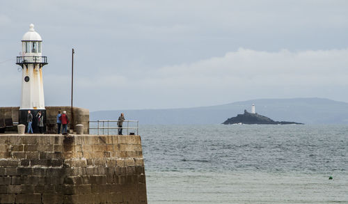 Lighthouse in sea against sky