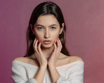 Portrait of beautiful woman standing against colored background