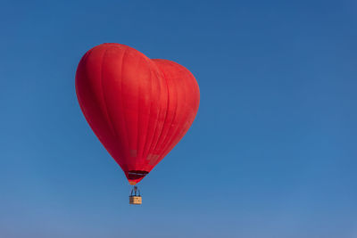 Low angle view of hot air balloons against clear blue sky