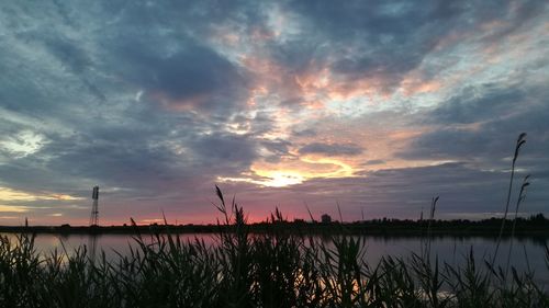 Scenic view of lake against dramatic sky during sunset