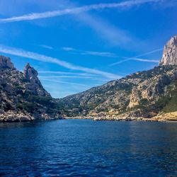 Scenic view of sea and mountains against blue sky