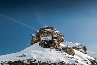 Low angle view of snowcapped mountain against blue sky