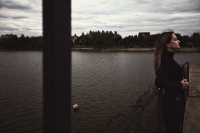 Portrait of young woman standing against lake