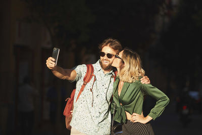 Woman holding smart phone while standing outdoors