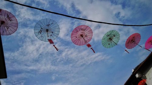 Low angle view of umbrellas hanging against blue sky