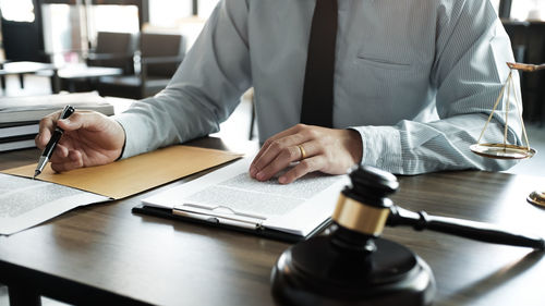 Midsection of man holding umbrella on table