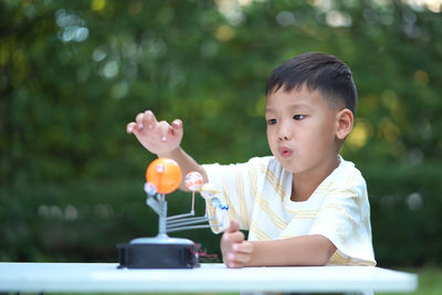 Close-up of cute boy playing with model on table in park