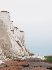 Cliff by sea against clear sky