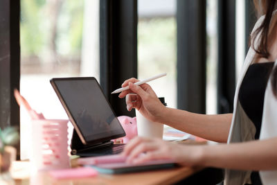 Midsection of woman using smart phone on table