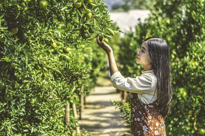 Young woman standing against trees