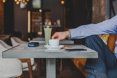 Midsection of businessman holding coffee cup on table in cafe