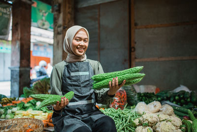 Portrait of young woman holding vegetables at market